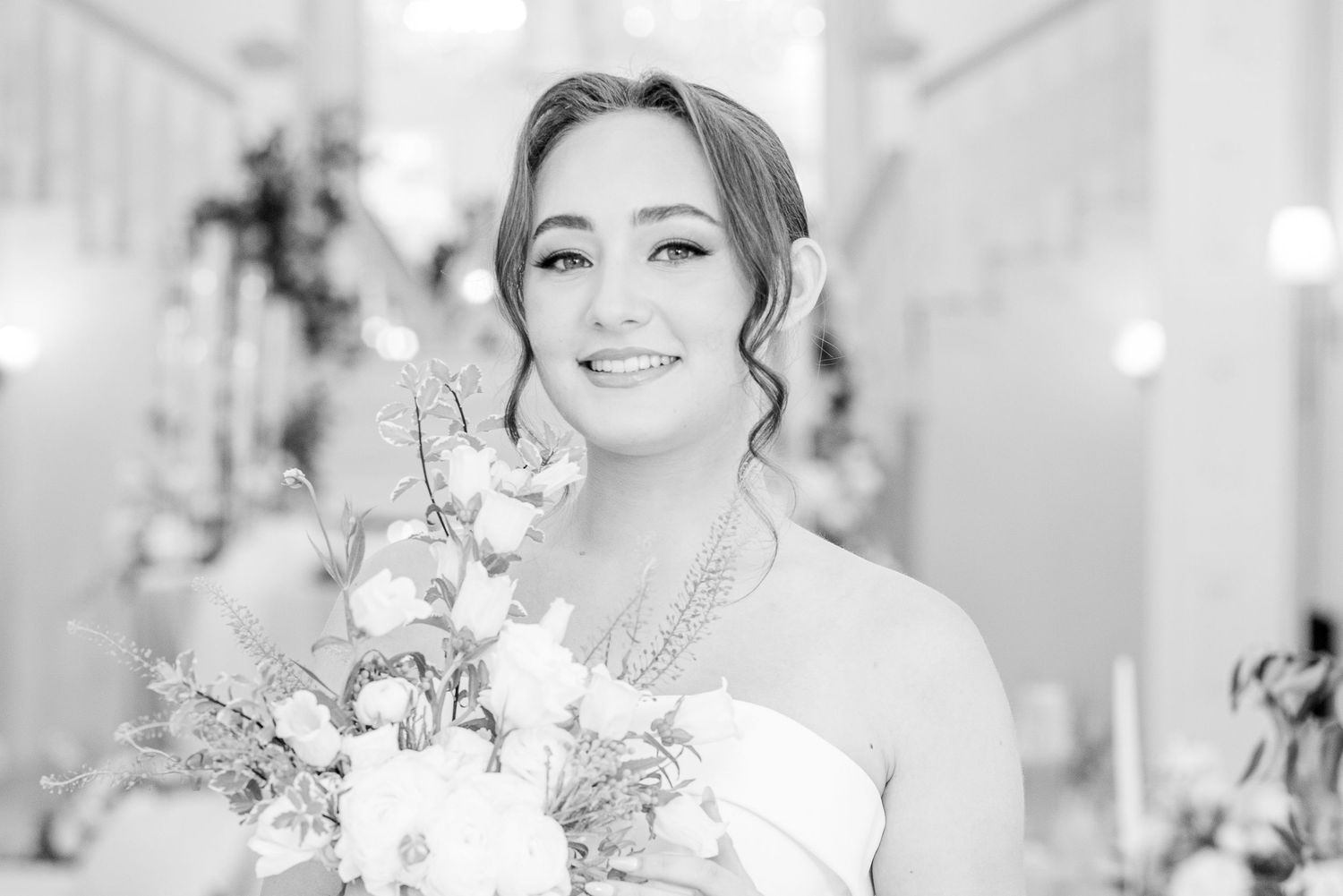 Black and white bridal portrait with elegant bouquet in light-filled venue.
