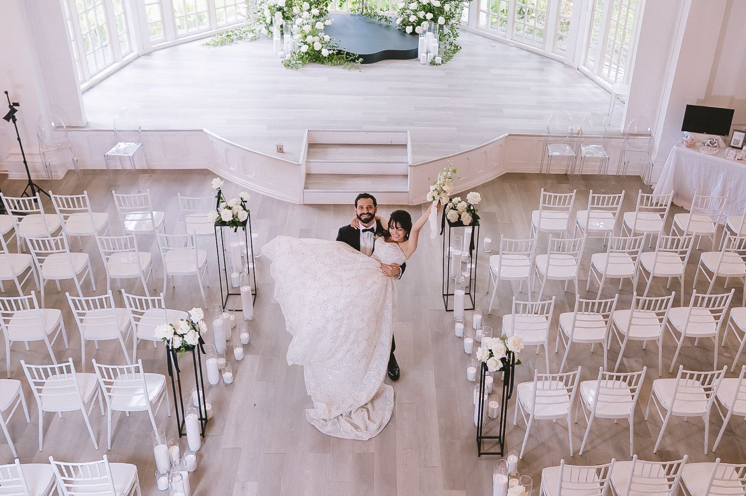Wedding ceremony setup with white chiavari chairs and ethereal floral decorations.