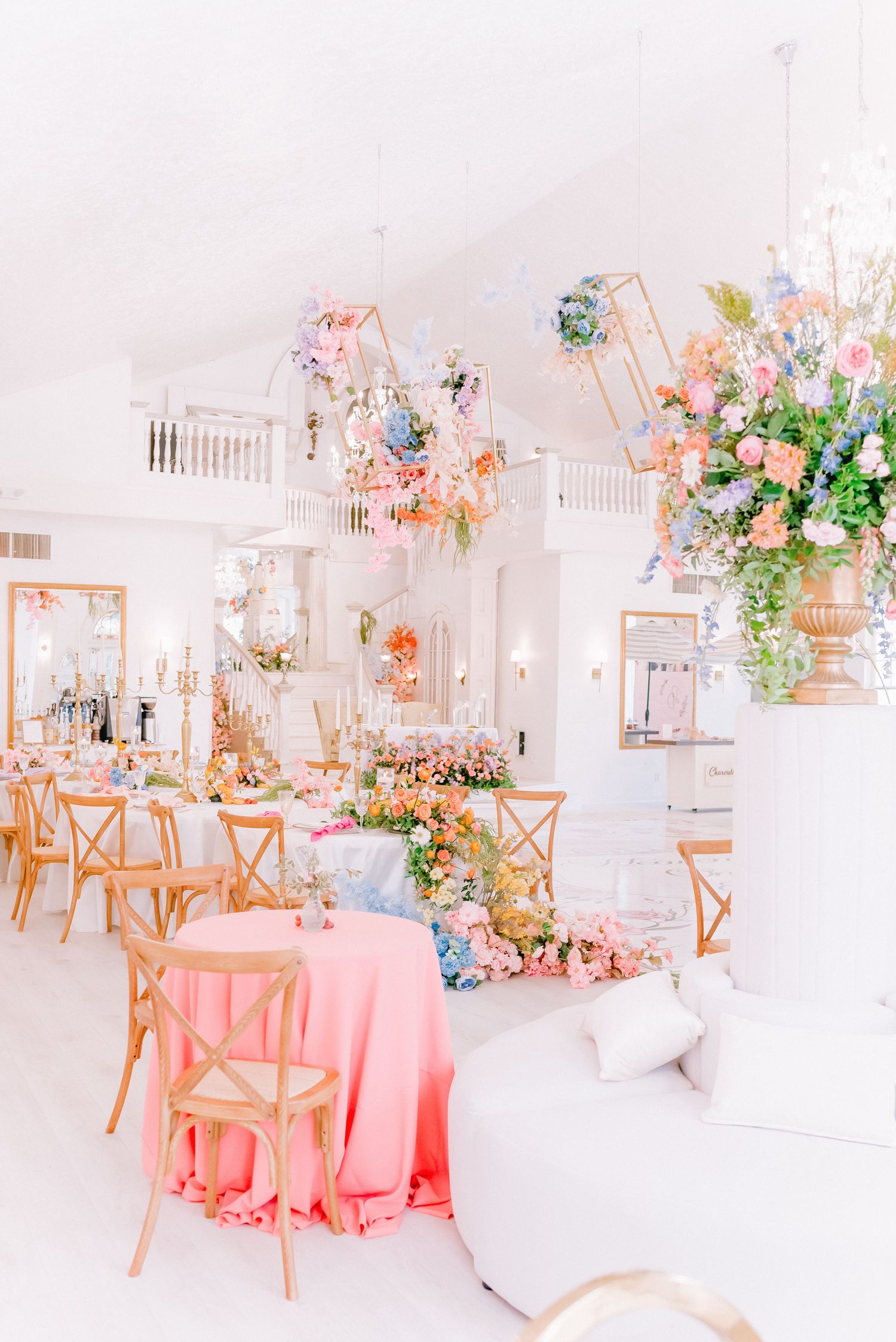 Light and airy wedding reception space with pink accents and floral arrangements.