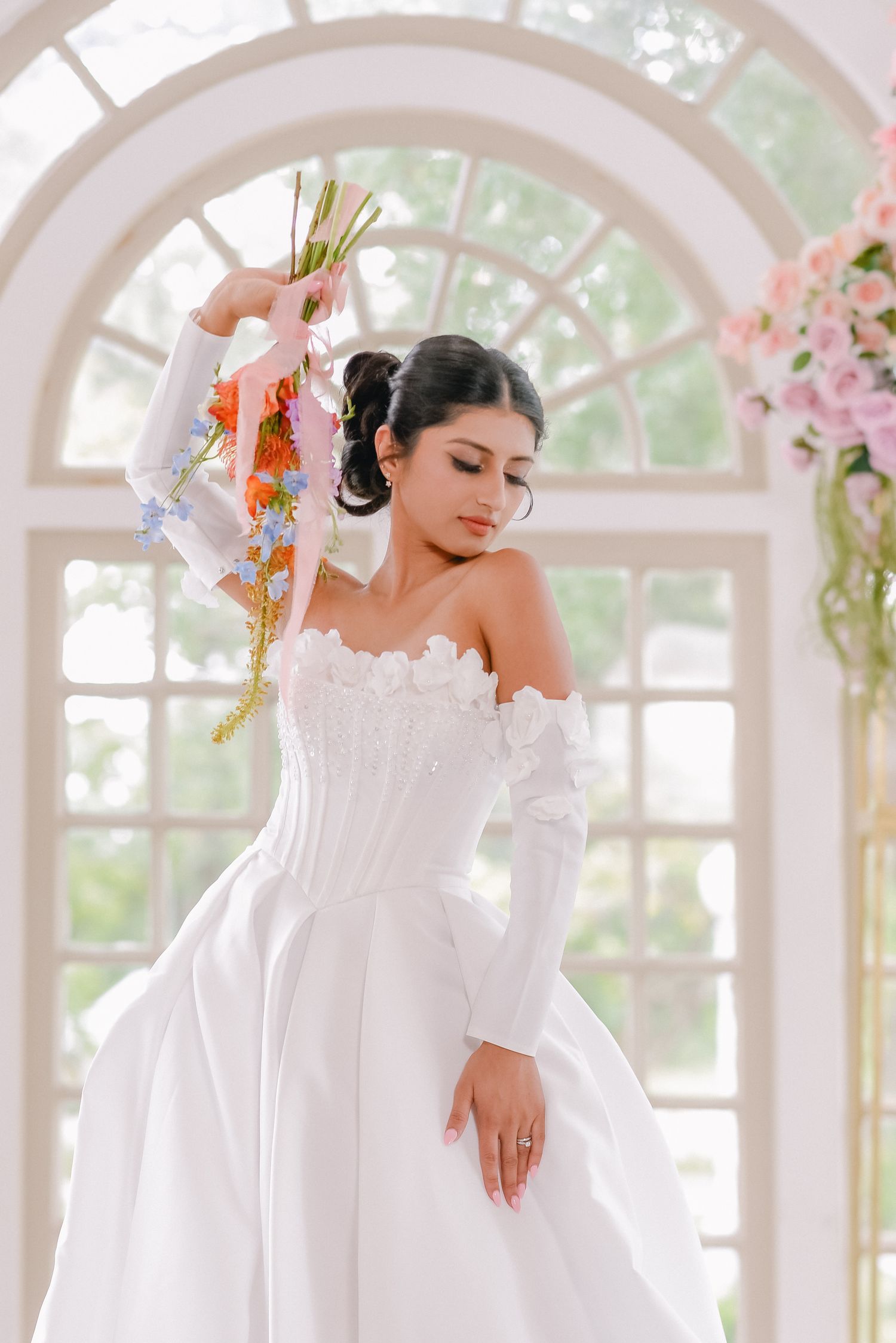 Elegant bridal portrait in front of arched windows with natural light streaming in.