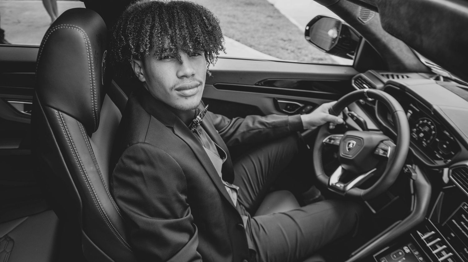 Black and white close-up of luxury car interior and steering wheel.