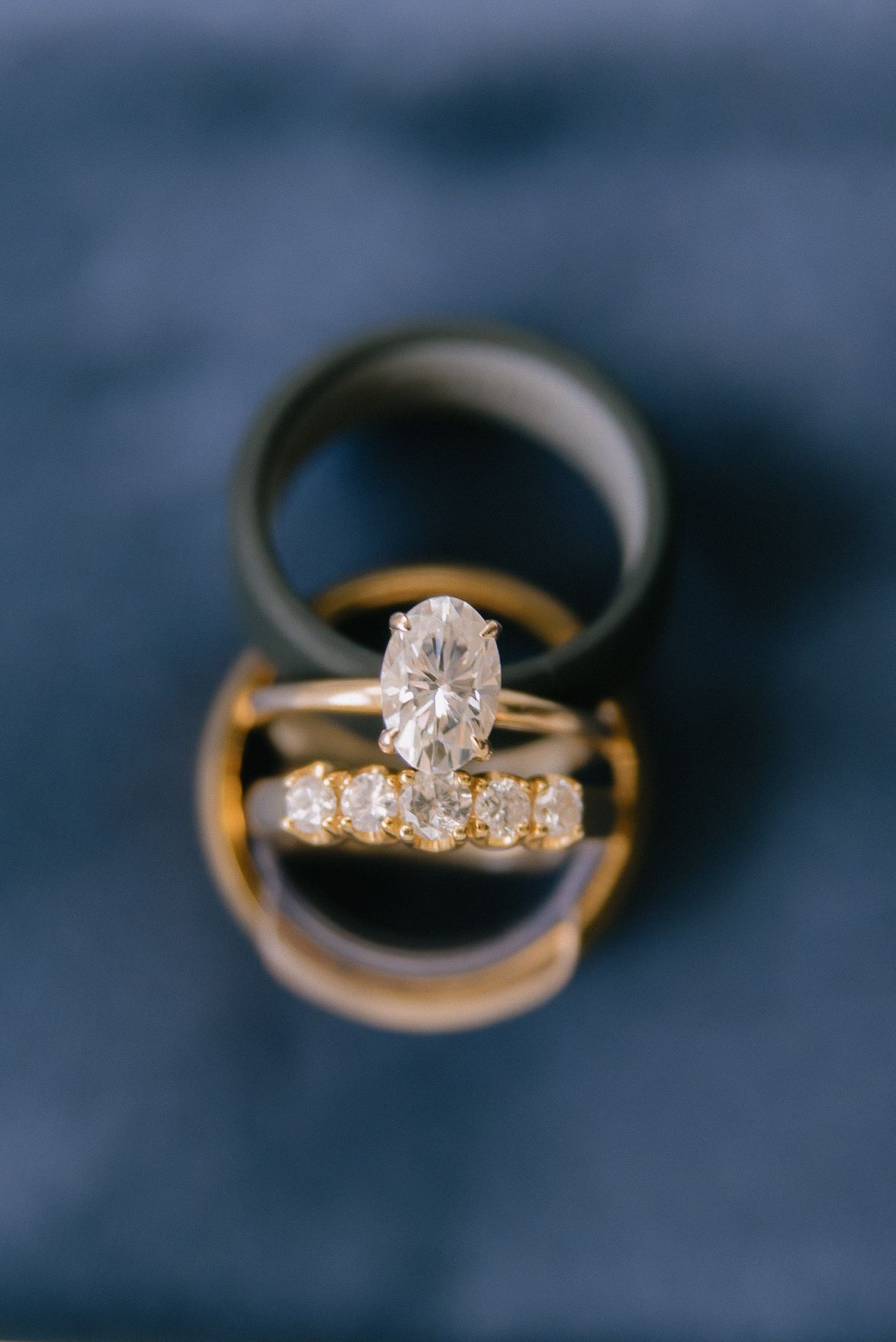 Close-up shots of diamond engagement rings and wedding bands on dark blue background.