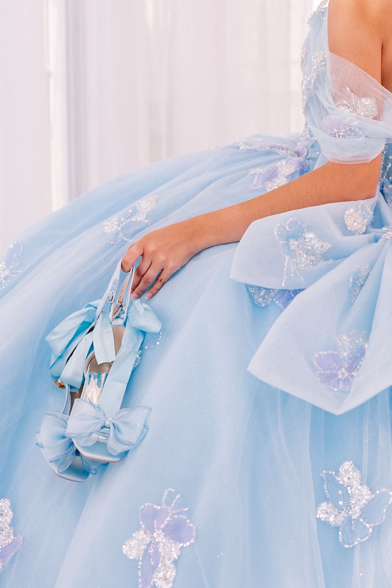 Detailed view of a light blue formal dress with delicate butterfly appliques and bow accents.