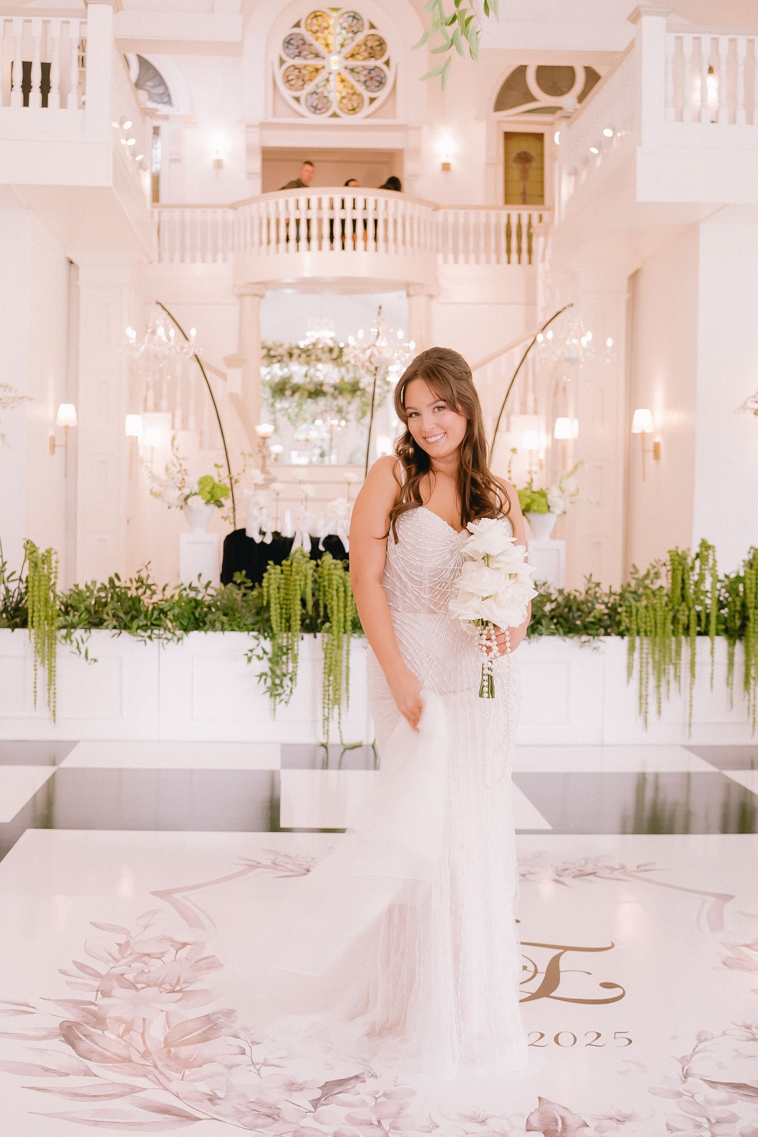 Elegant white wedding venue interior with crystal chandeliers and floral arrangements creating a romantic atmosphere.