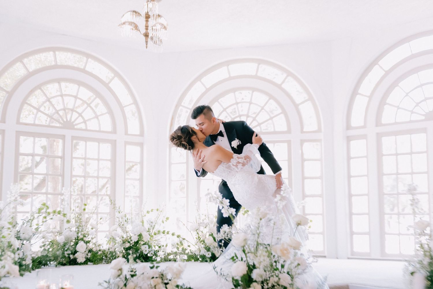Bright wedding venue with arched windows and romantic floral arrangements.