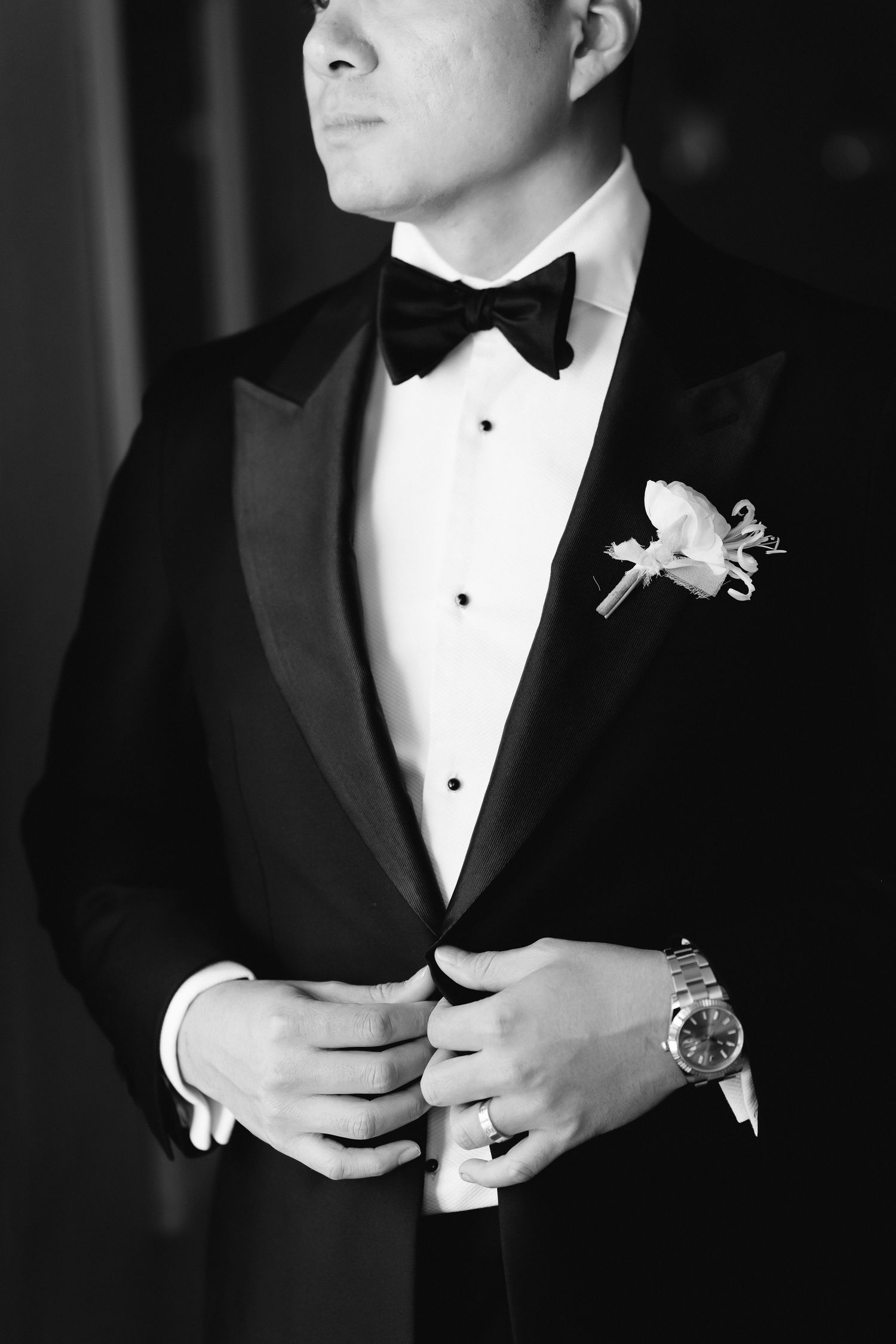 Black and white detail shots of groom adjusting tuxedo and boutonniere.