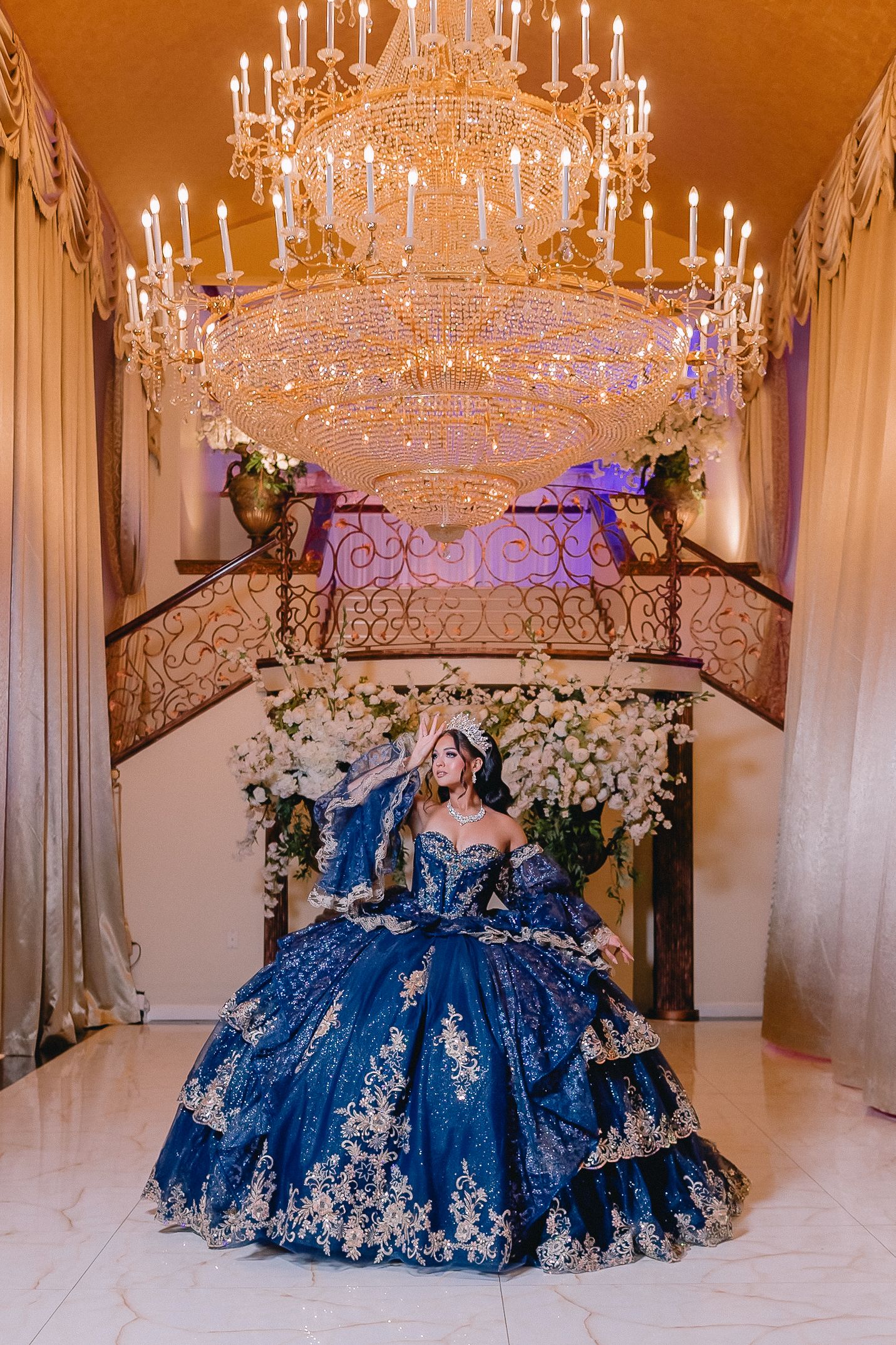 Royal blue quinceanera dress showcased under ornate crystal chandeliers.