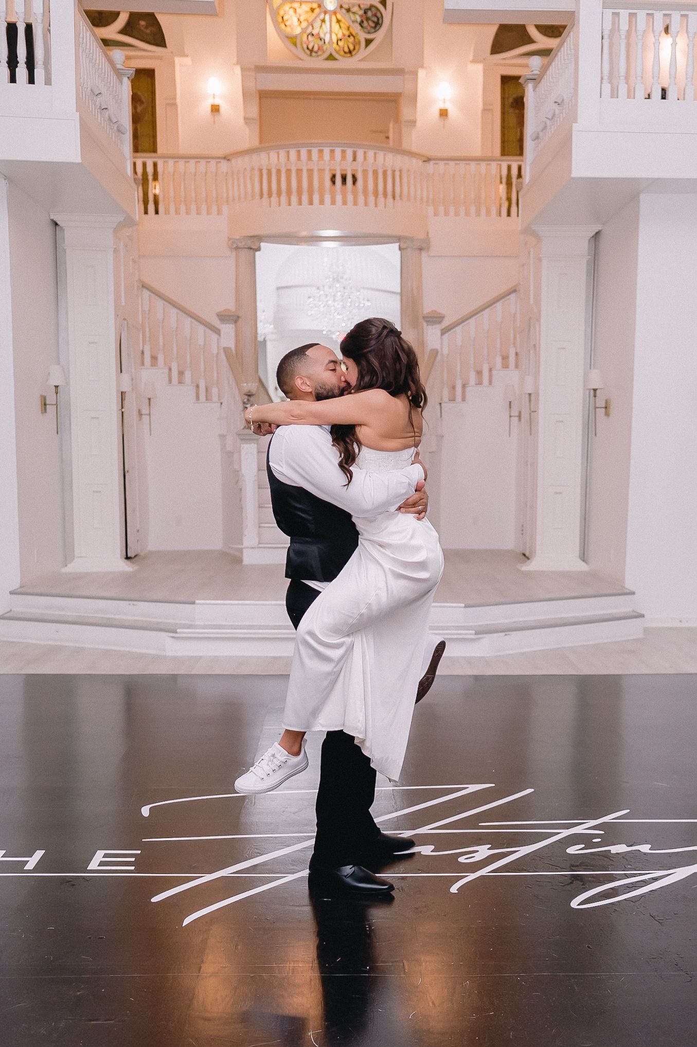 Romantic dance sequence in an elegant white ballroom with ornate architectural details.