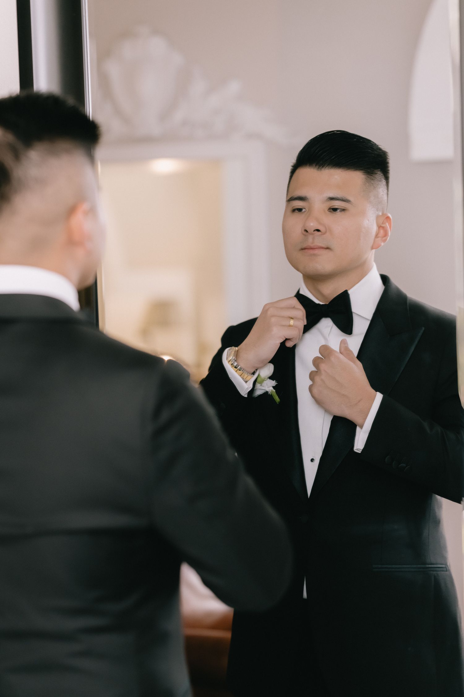 Wedding party members in black tuxedos adjusting their attire before the ceremony.