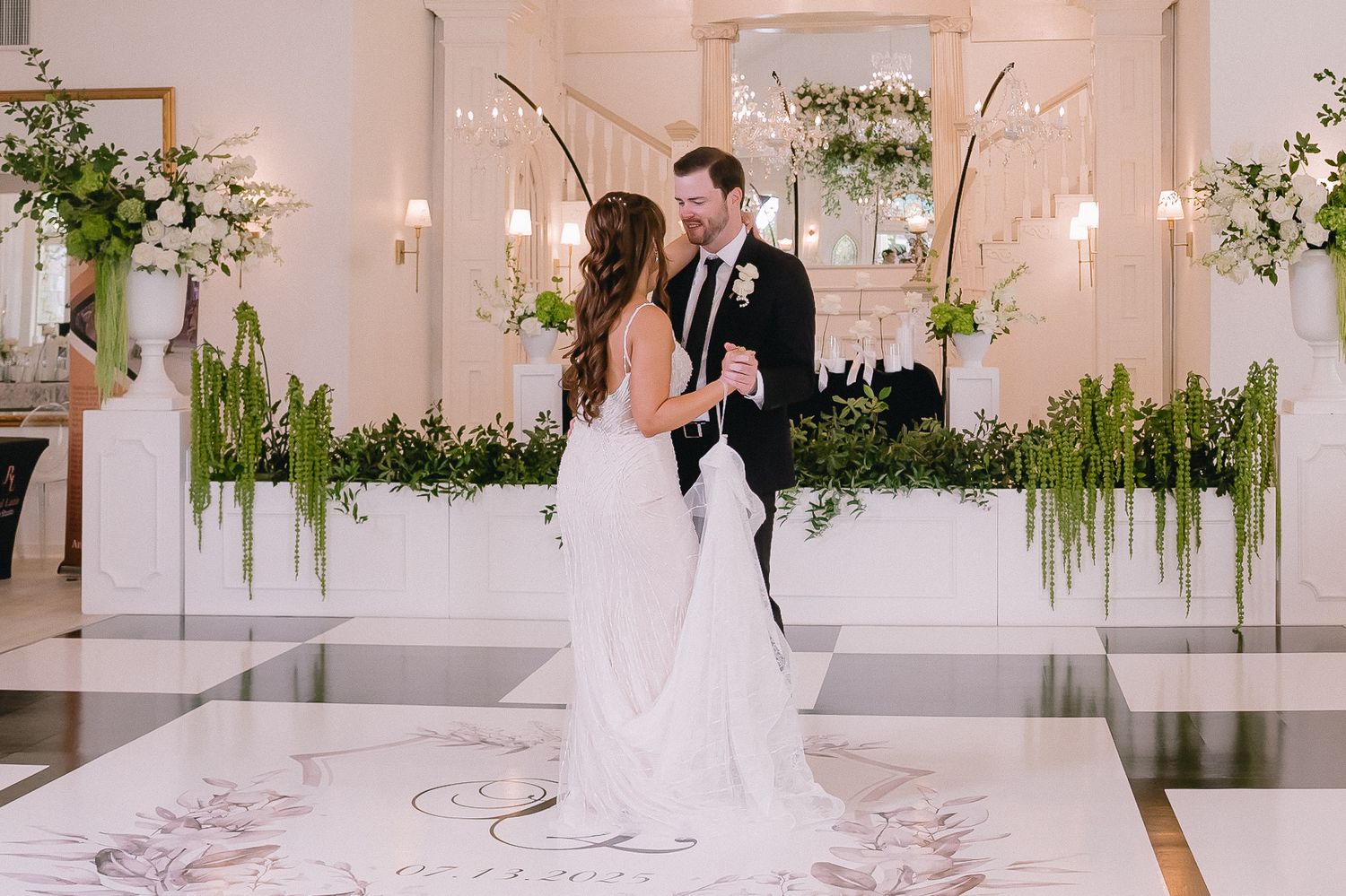 Minimalist white wedding venue with contemporary decor and hanging botanical arrangements.