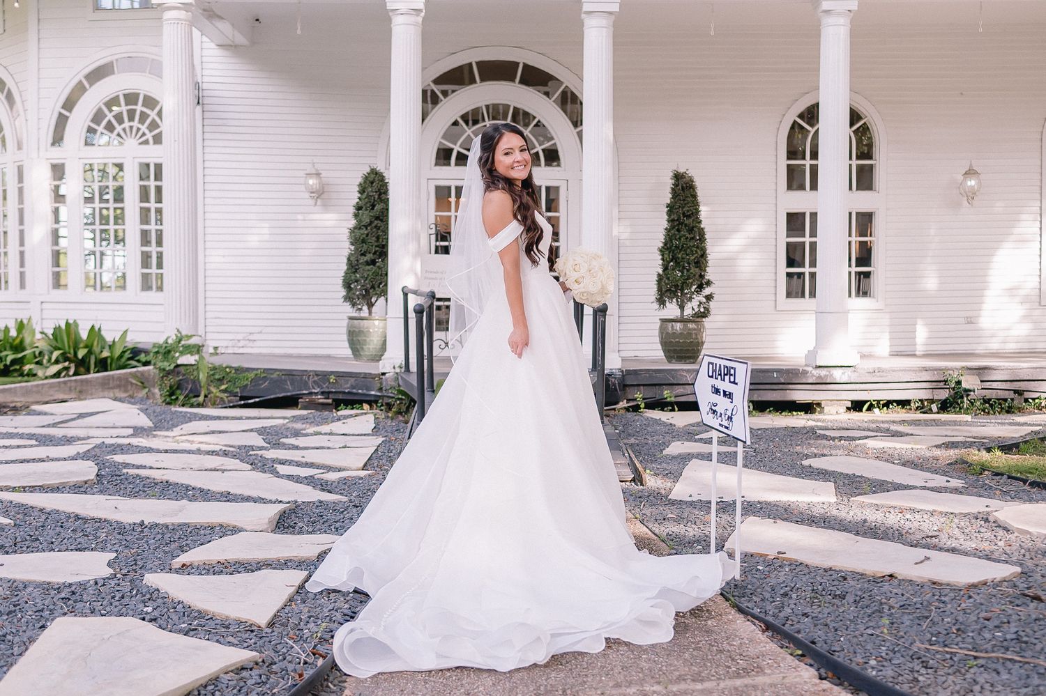 Elegant wedding venue exterior features white columns and arched windows with decorative details.