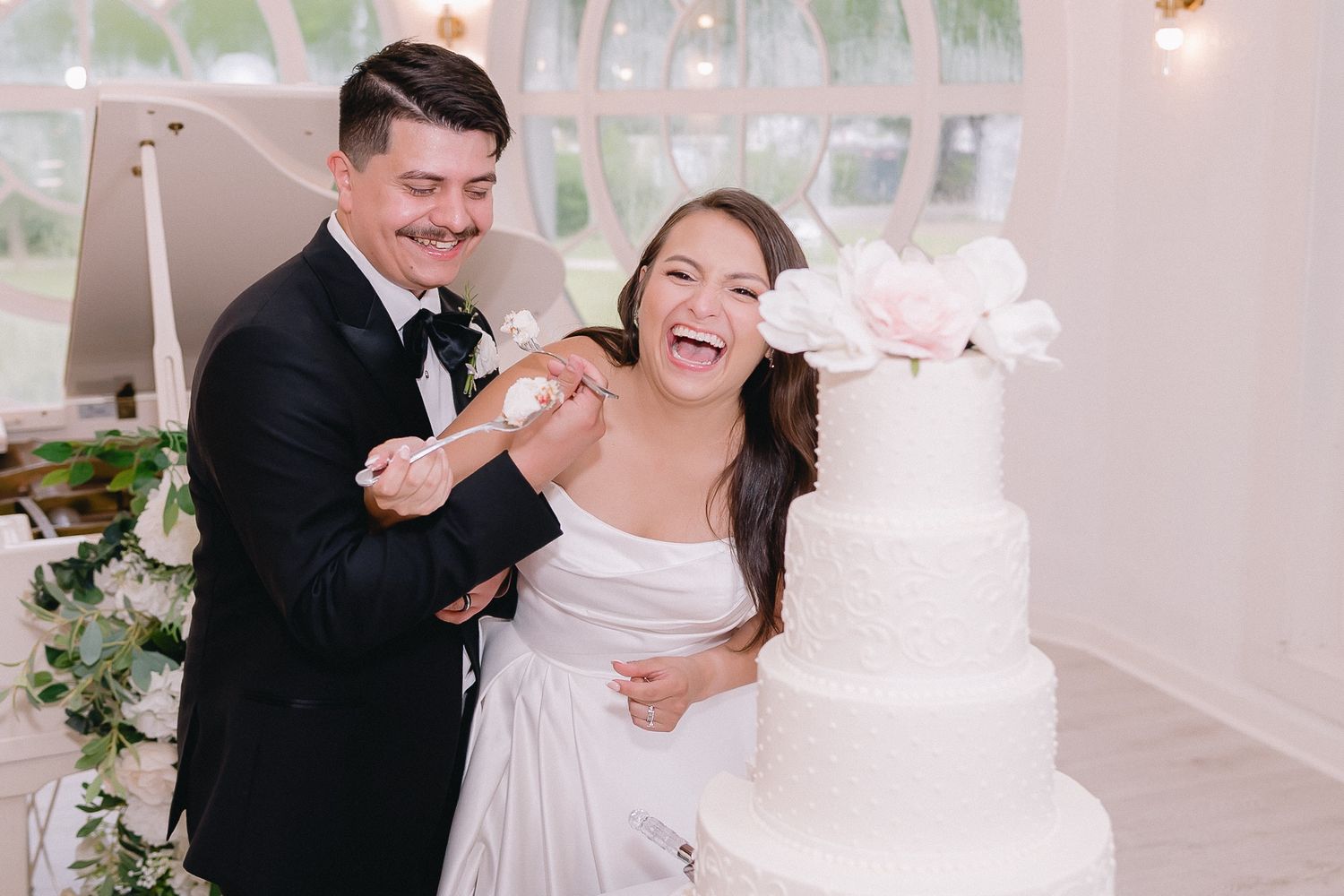 Wedding cake cutting celebration in an elegant white ballroom setting.