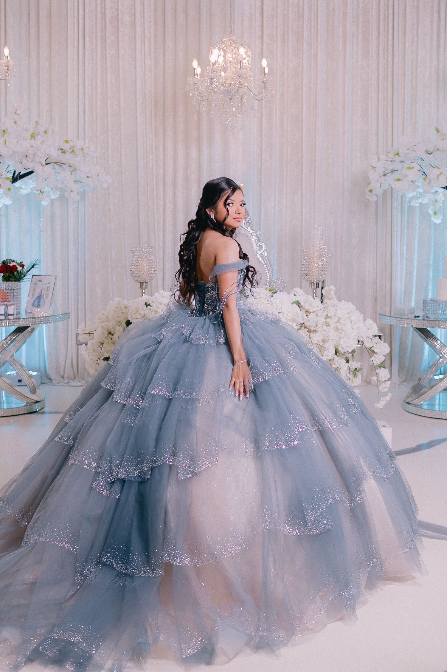 Stunning blue princess ball gown photographed in an elegant white room with chandeliers.
