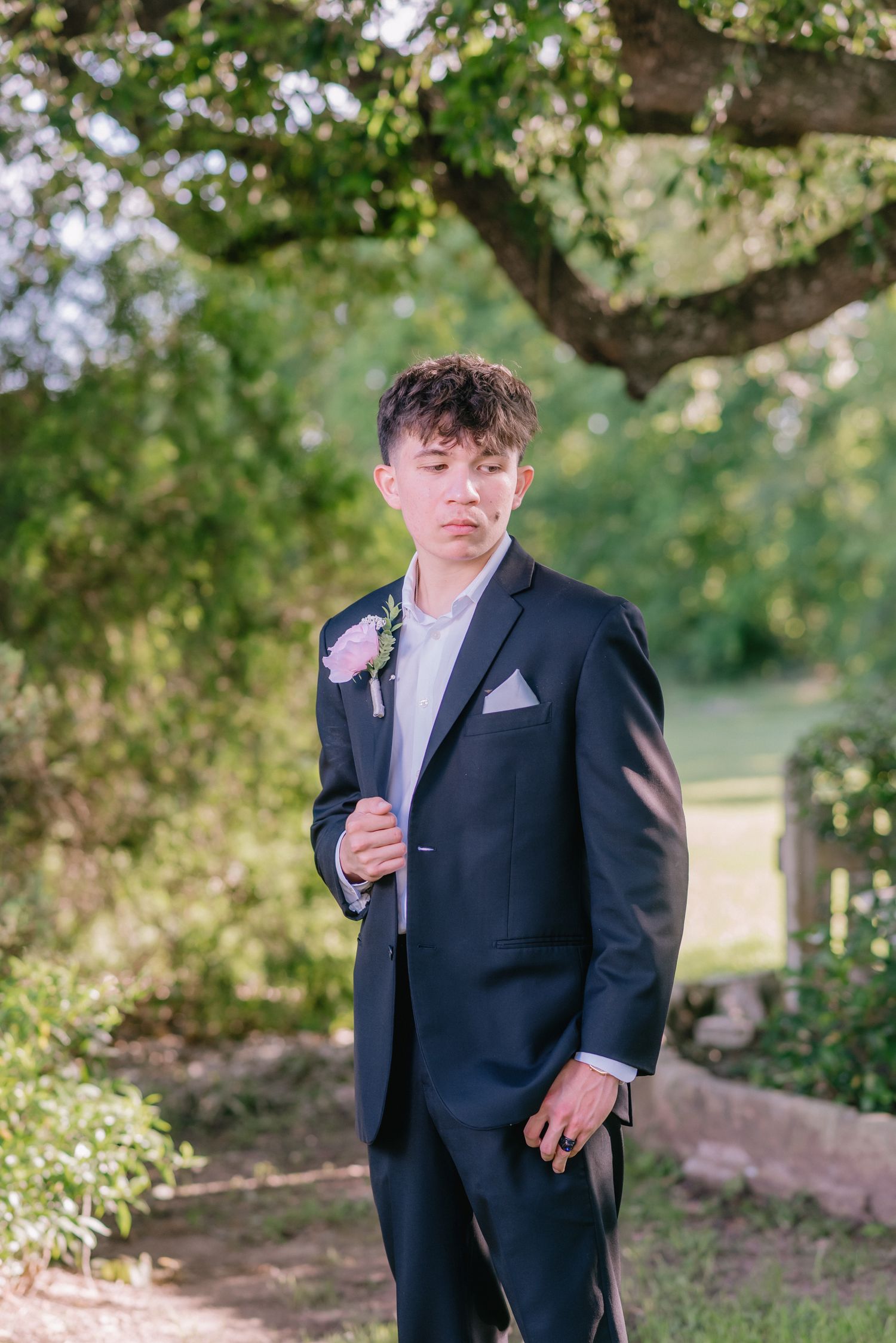 A formal portrait series showing someone in a black suit and tie in a garden setting.