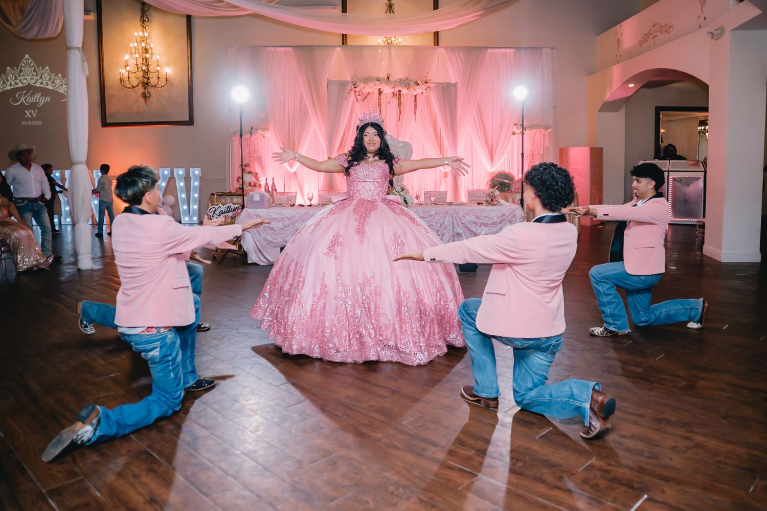Dance celebration with pink decor and dramatic lighting in a spacious ballroom.