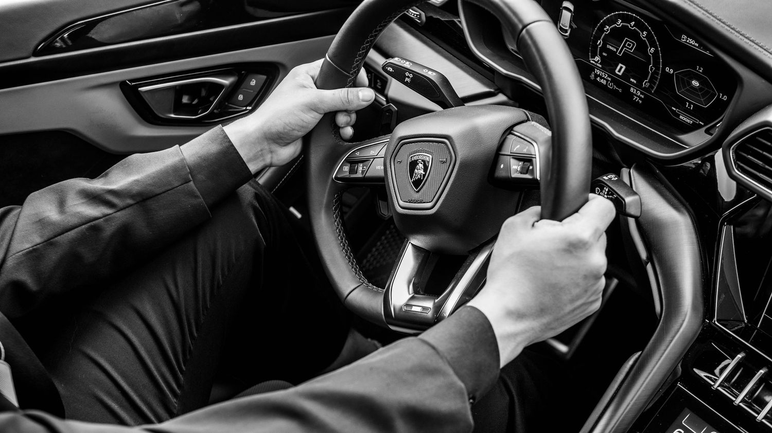 Modern car dashboard and steering wheel details in black and white.