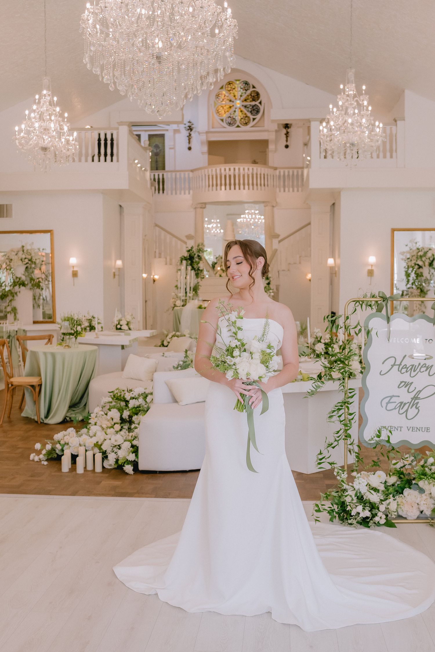 Elegant bridal photoshoot in a white room with crystal chandeliers and floral decorations.
