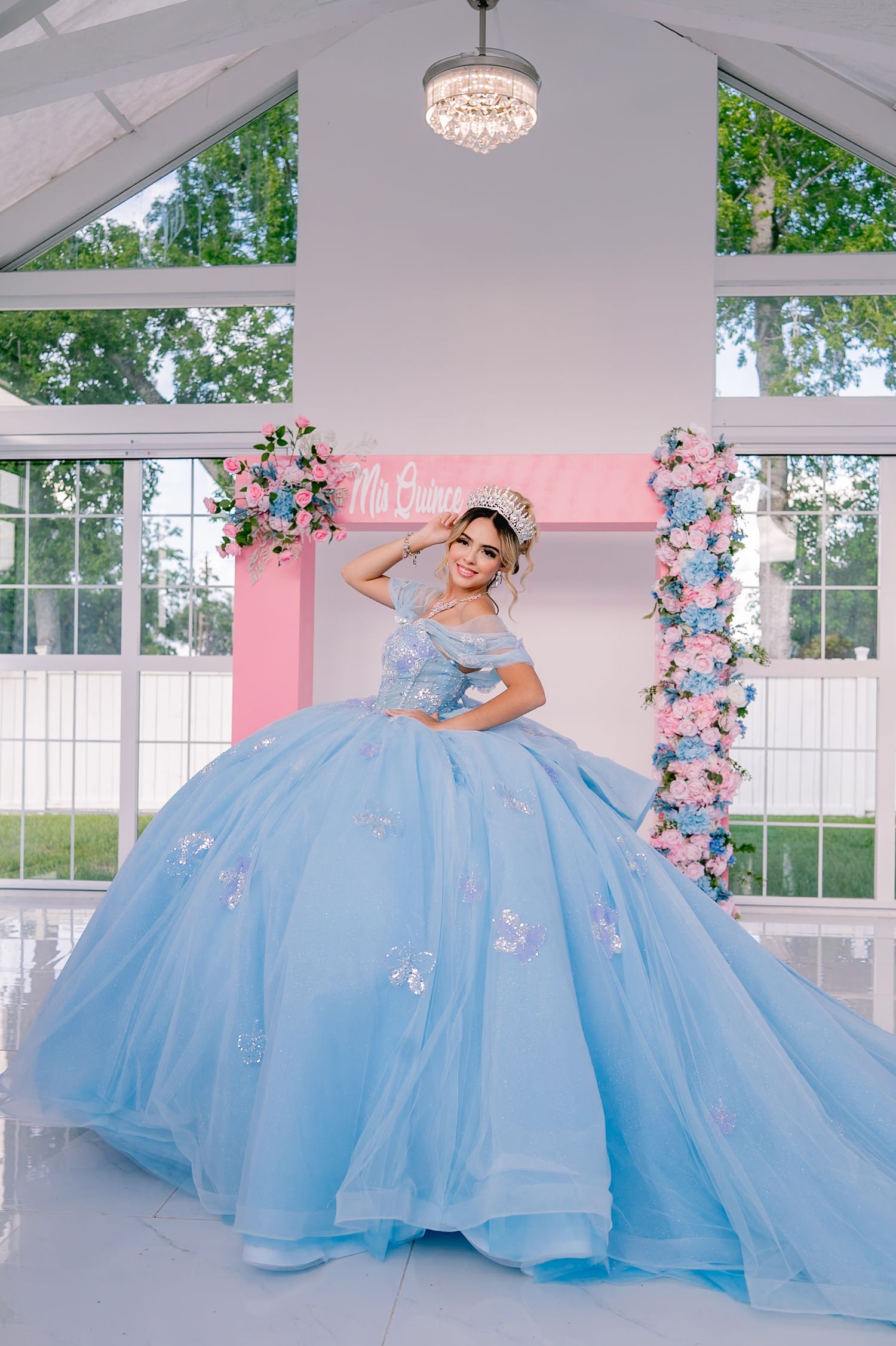 A stunning light blue ball gown with sparkly details photographed in an elegant white room with pink floral accents.