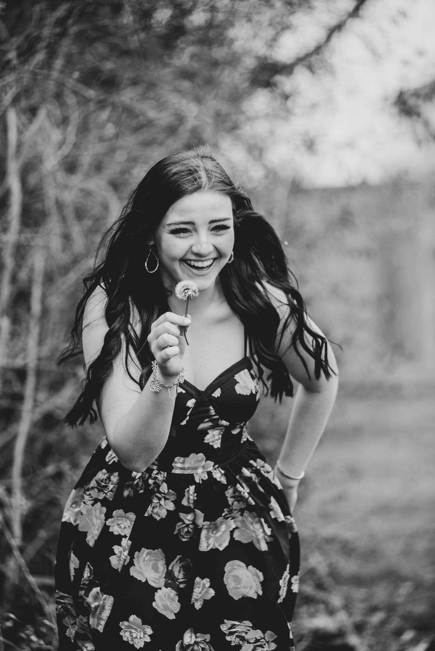 A black and white portrait of someone wearing a floral dress outdoors.