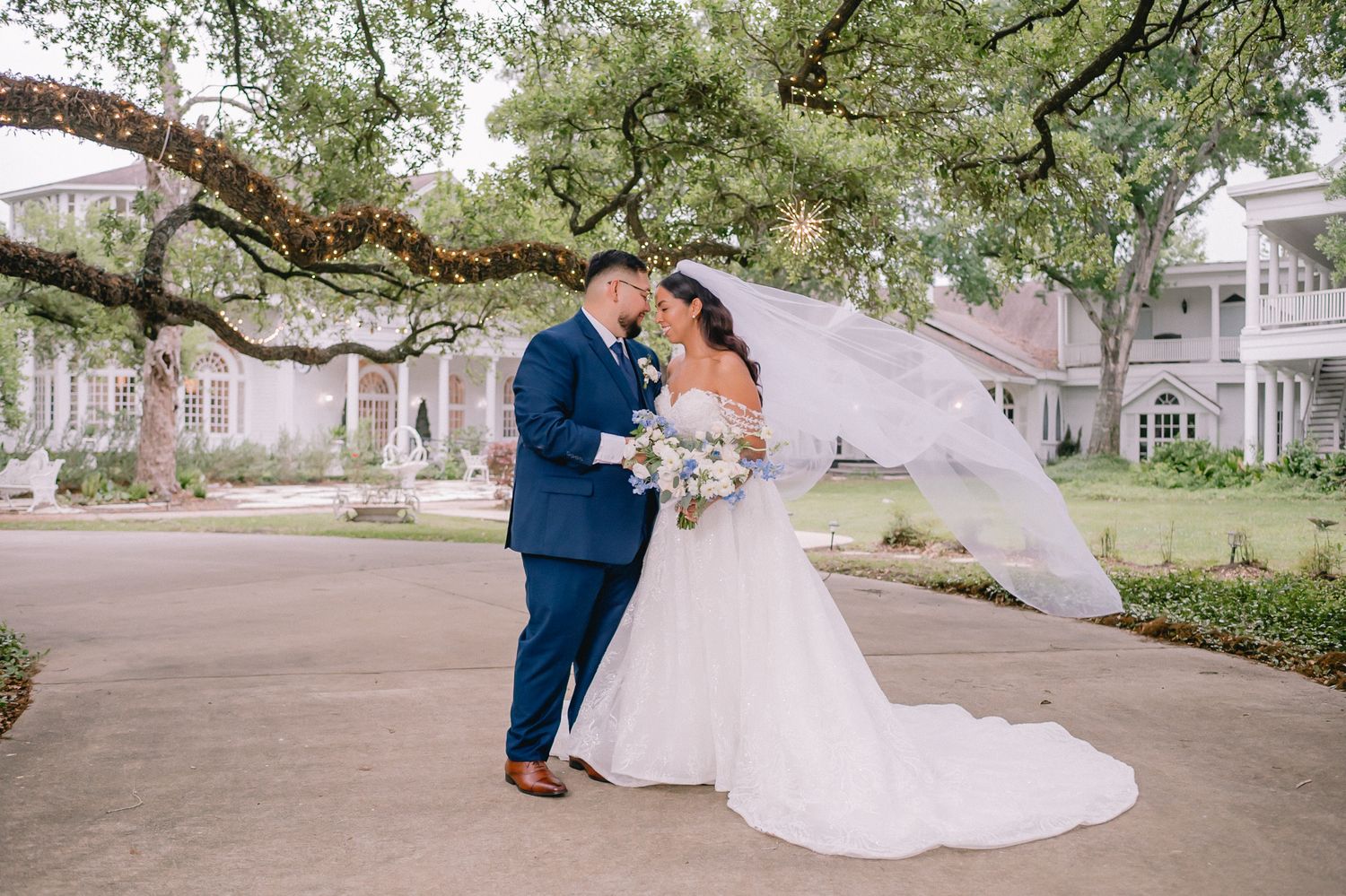 Wedding couple walking under Spanish moss trees in a romantic outdoor setting.