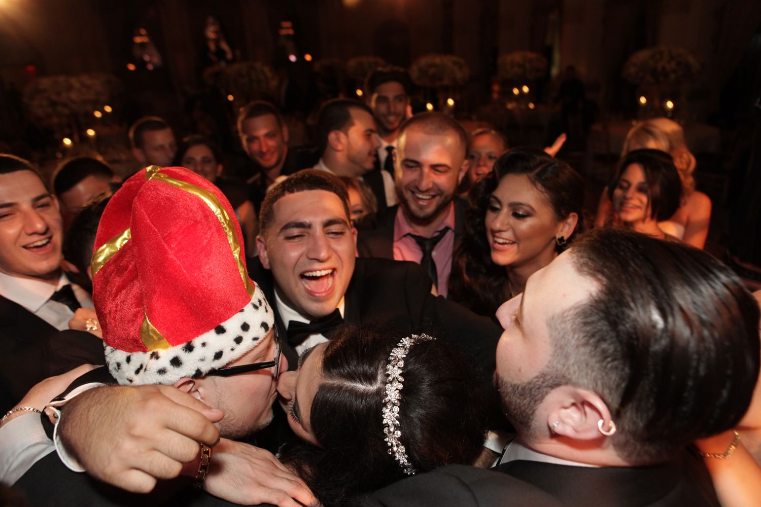 Energetic wedding reception crowd celebrates with festive holiday hats.