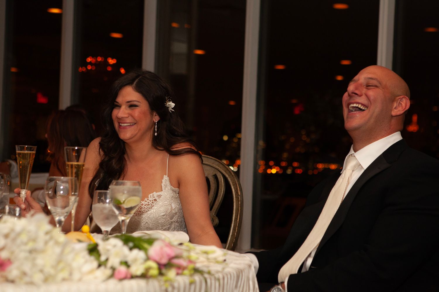 Wedding reception scene with couple sharing a joyful moment at their decorated head table.