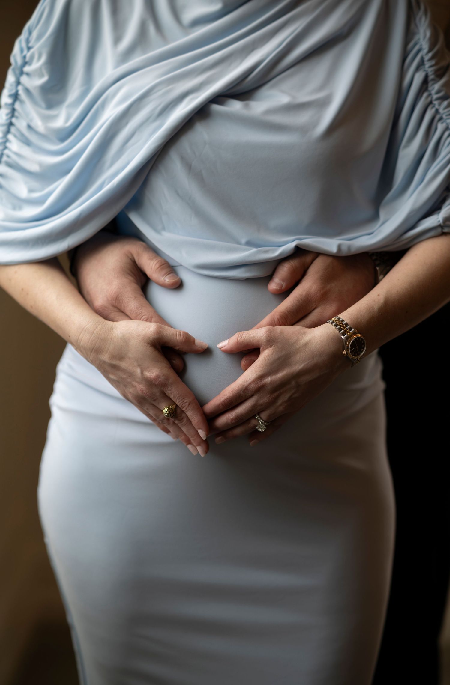 Hands gently cradling a pregnant belly in a light blue maternity dress, showing progression of pregnancy in multiple frames.