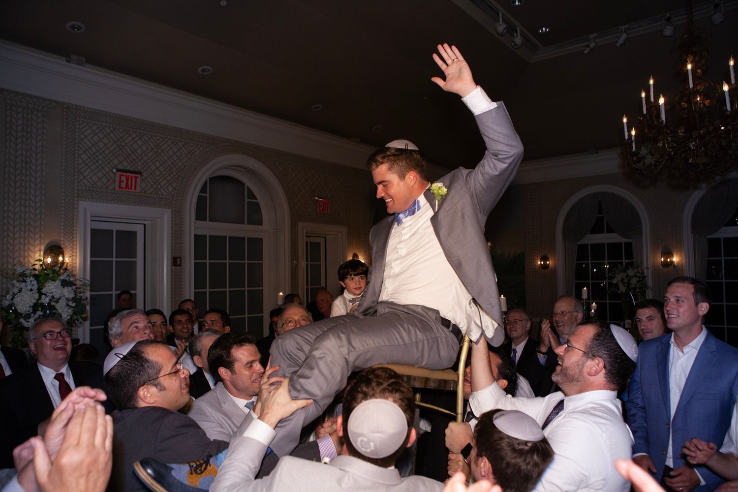 Wedding guests dance and celebrate with raised arms on the dance floor.