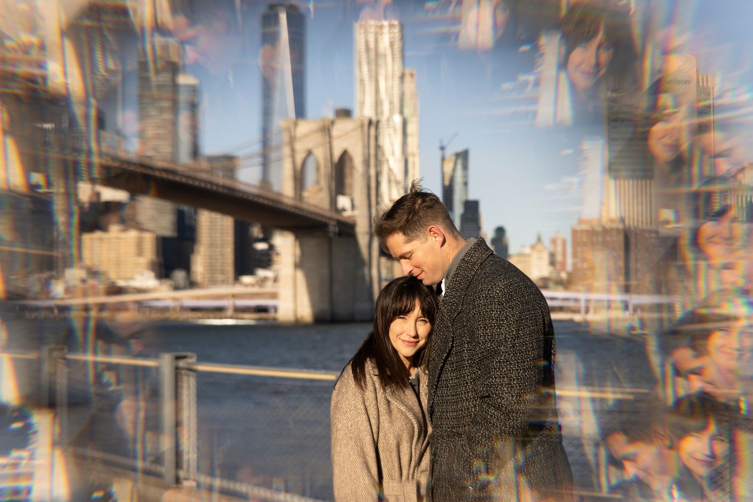A couple stands in an urban setting with multiple reflections and city buildings visible in the background.