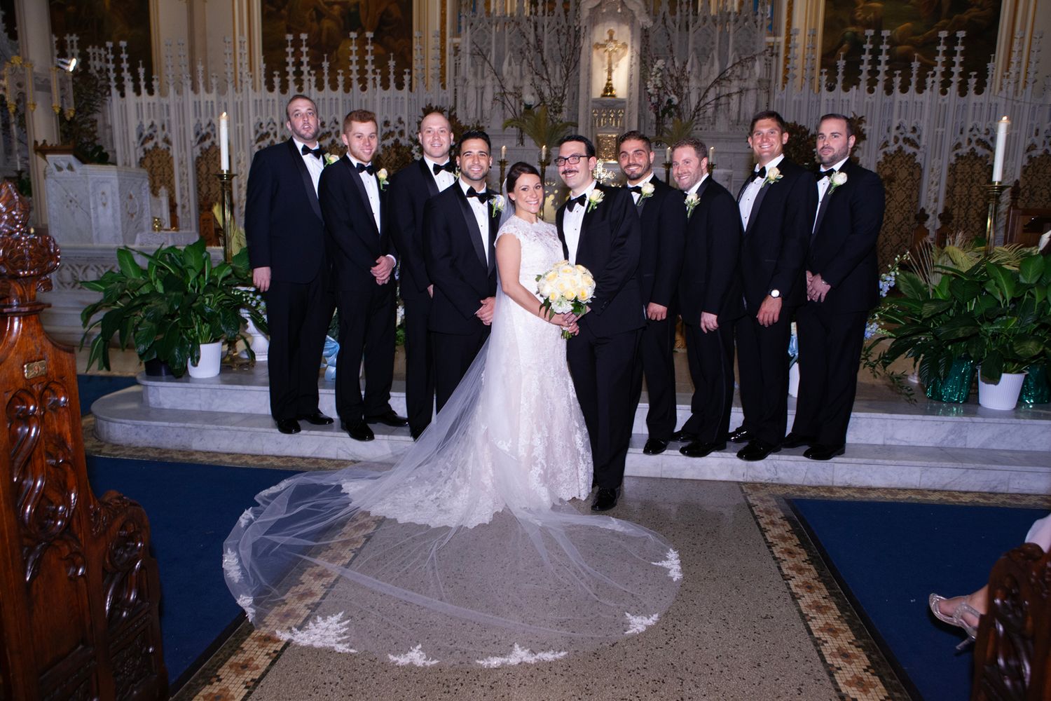 Wedding party gathered in an elegant church interior for formal photographs.