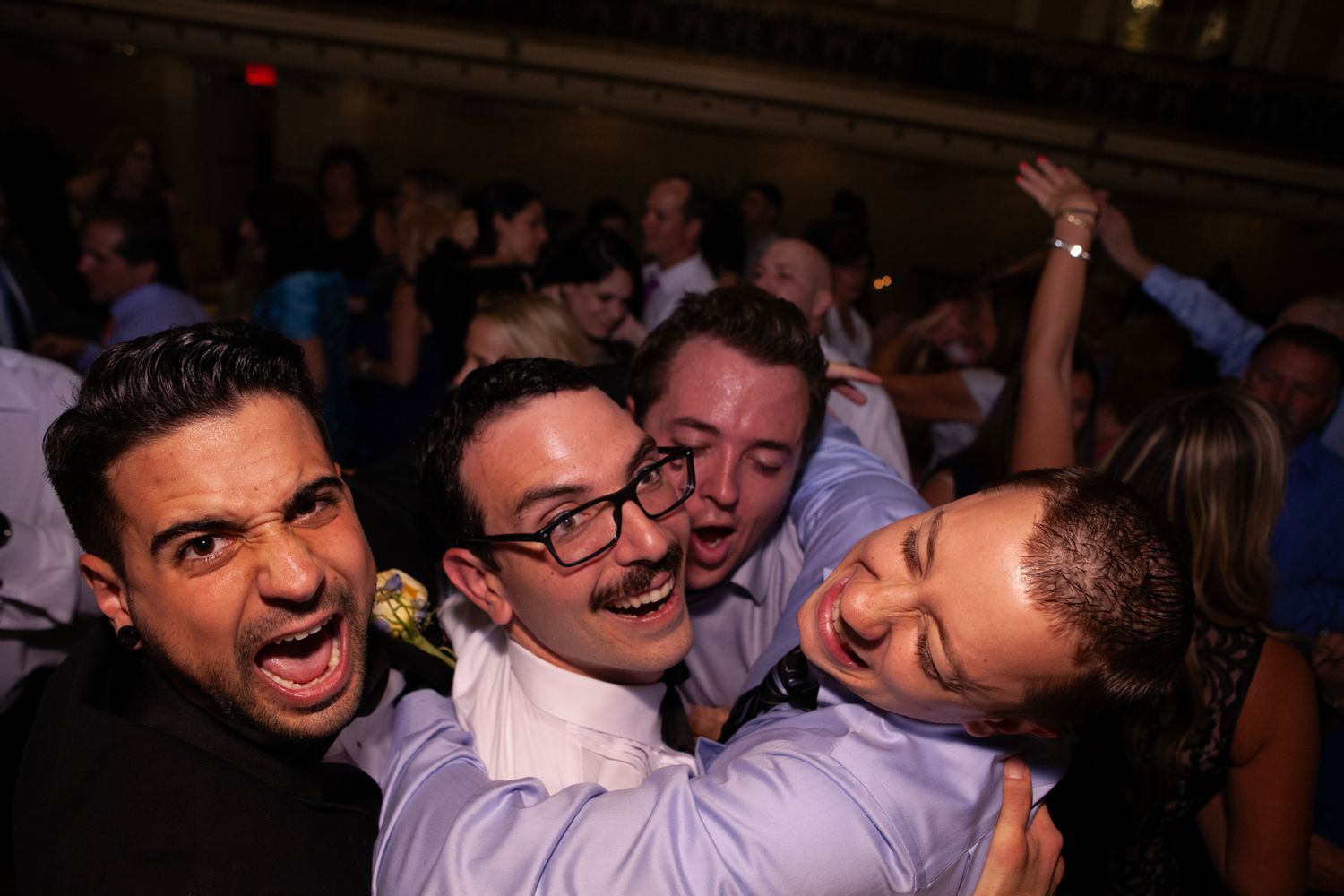 Lively wedding reception crowd laughing and celebrating on dance floor.