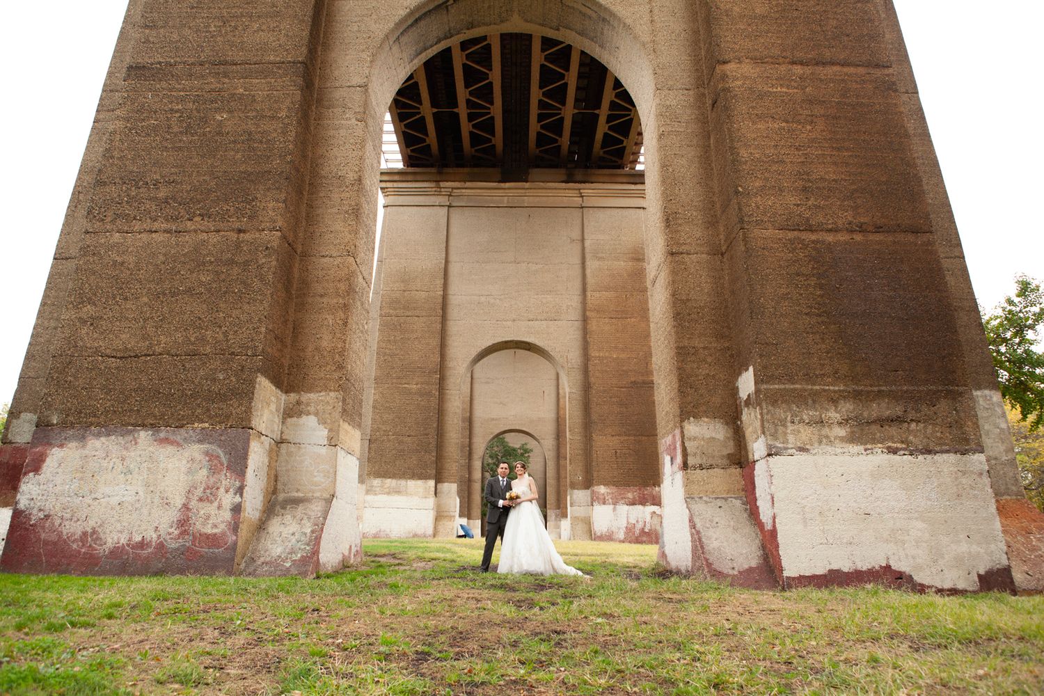 Symmetrical wedding photo under architectural arches with stone pillars.