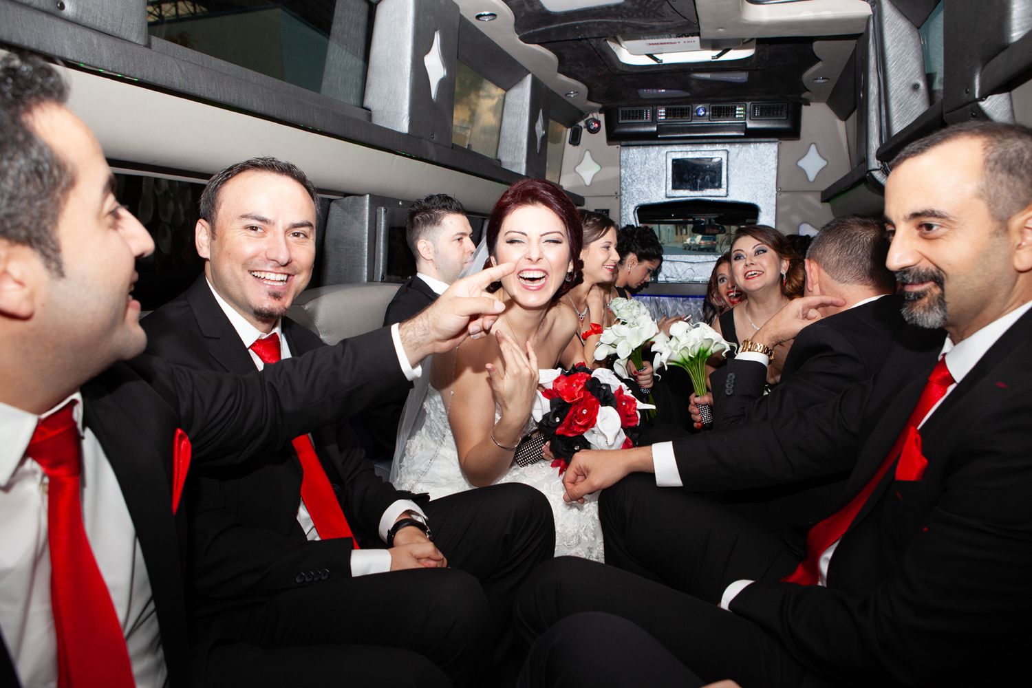 Wedding party celebrating and laughing inside a luxury limousine.