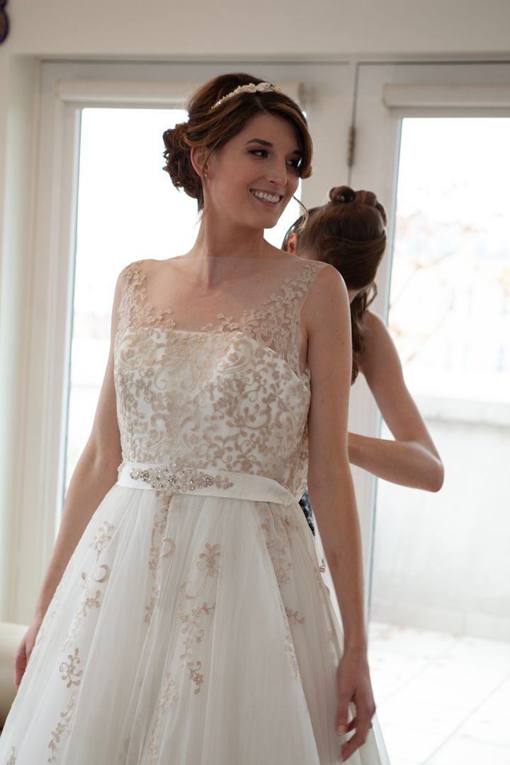 A beautiful wedding dress with delicate lace overlay and sheer neckline details photographed in natural window light.
