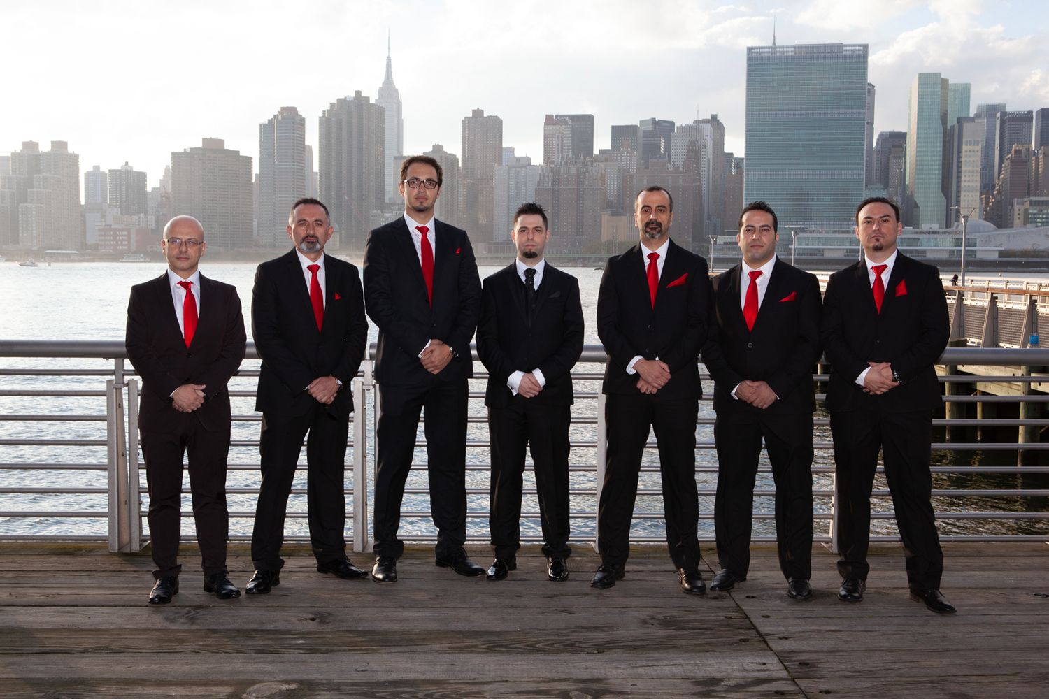 Groomsmen in formal attire stand in line against Manhattan skyline.