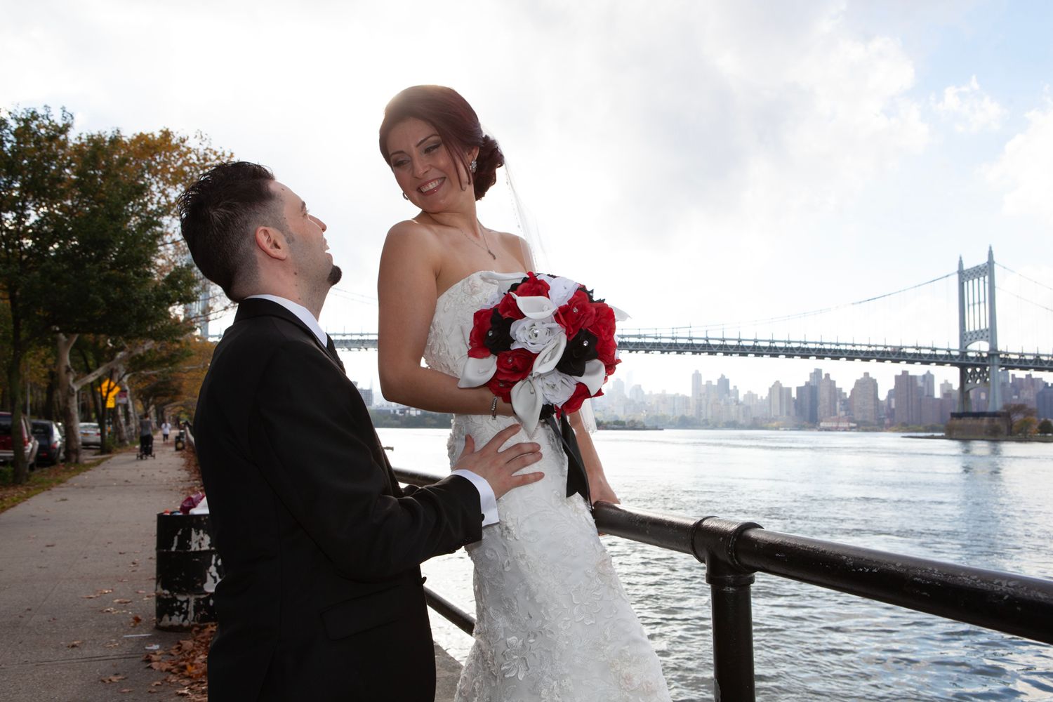 Wedding couple posing by waterfront with Manhattan Bridge in background.