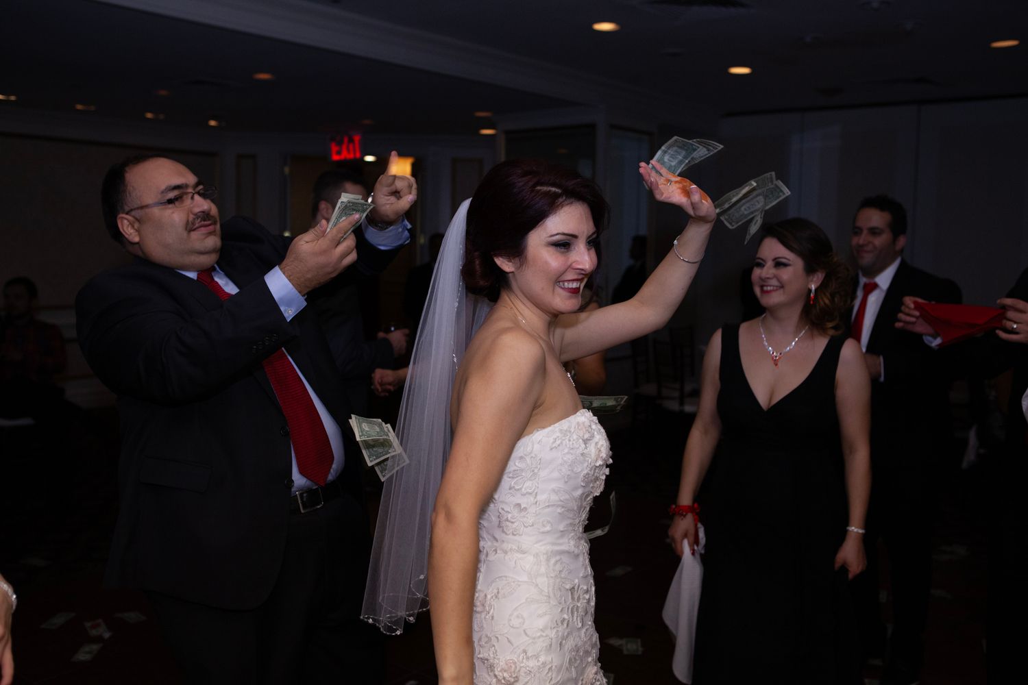 Wedding reception party on dance floor with bride in white gown dancing with other guests.