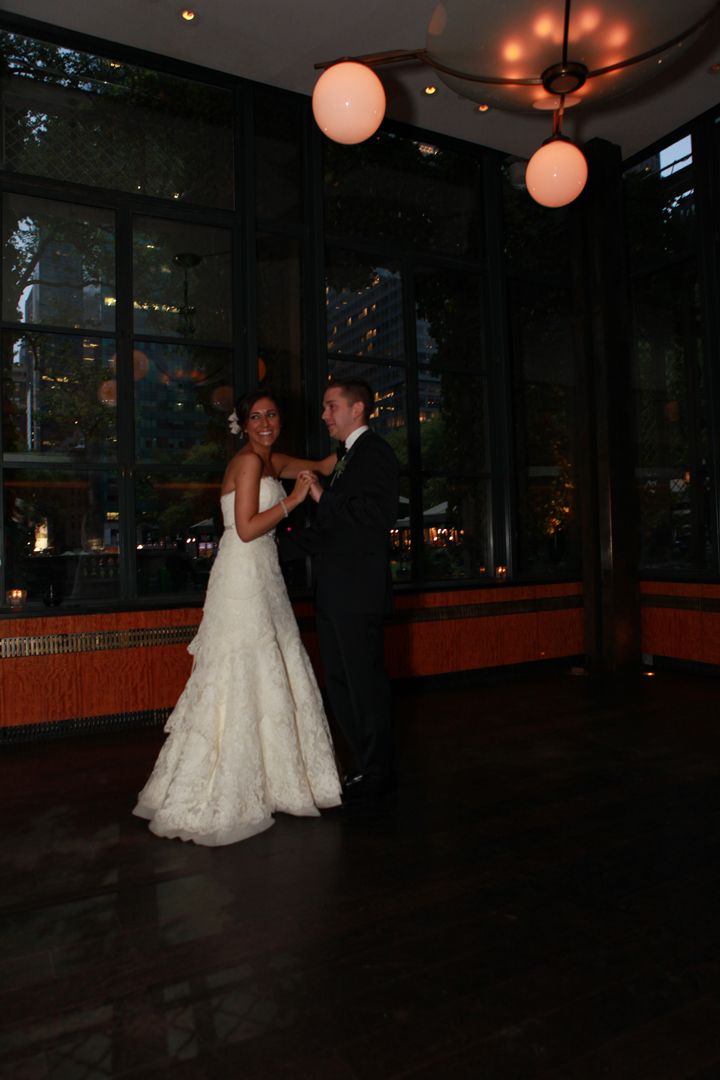 Wedding couple dances in dimly lit venue with glowing paper lanterns overhead.