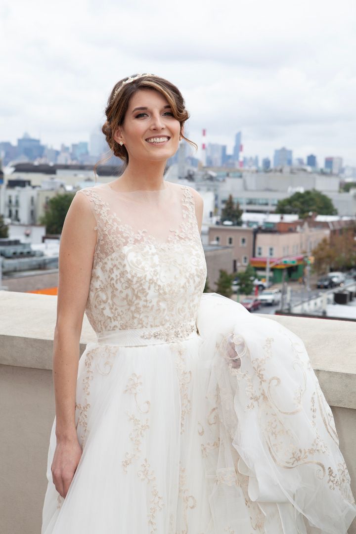 Elegant bridal portrait showcasing a detailed lace wedding gown against an urban cityscape backdrop.