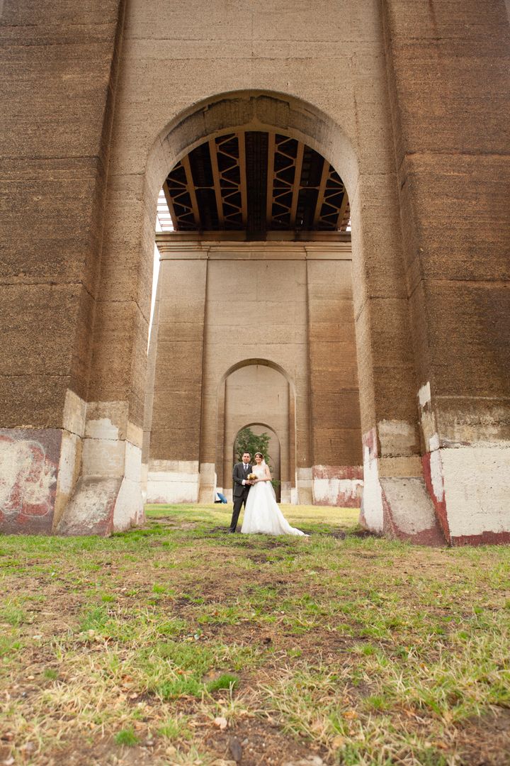 Architectural wedding photo featuring stone arches creating a dramatic tunnel effect.