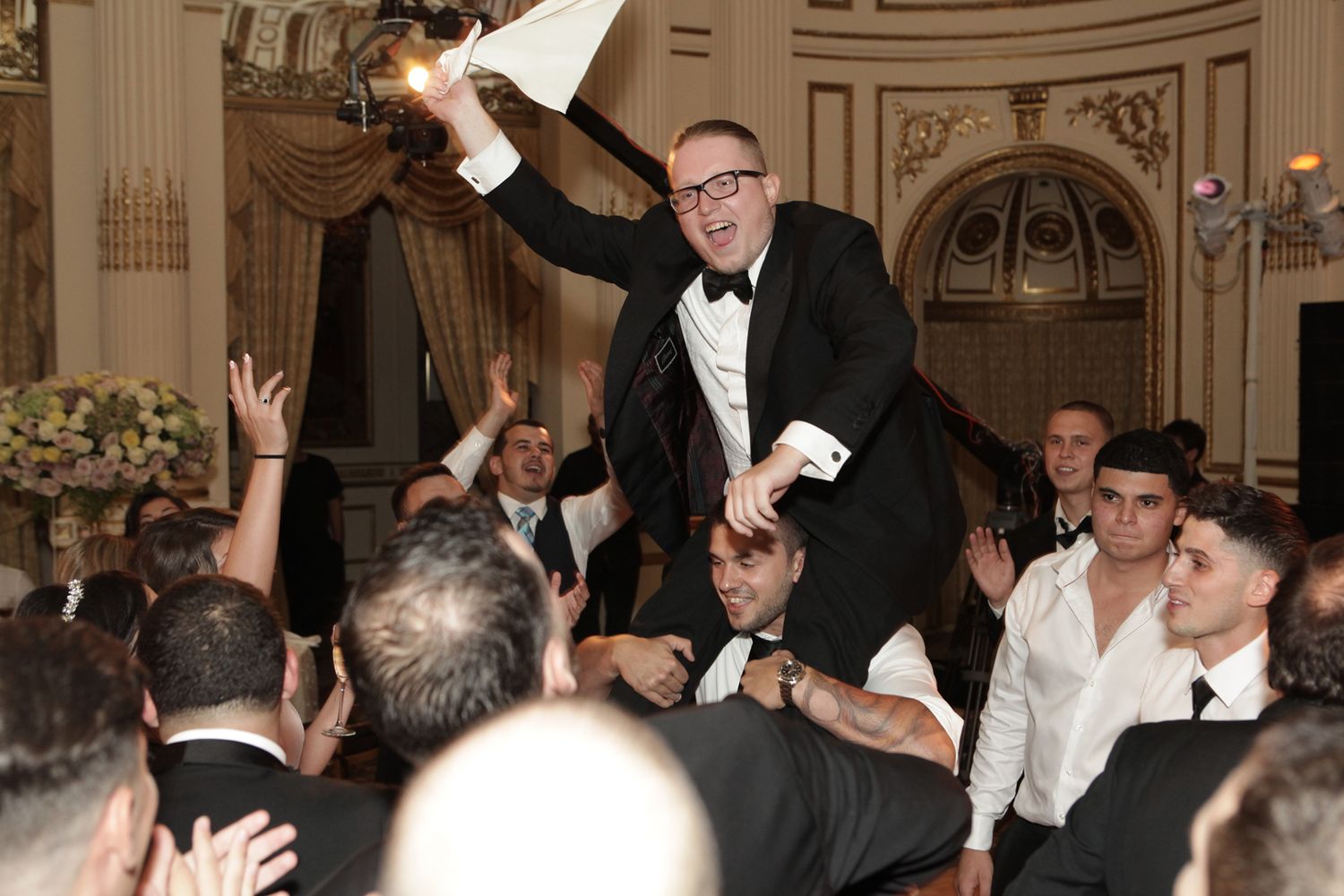 Wedding reception celebration with guest being lifted up during festive party moment.