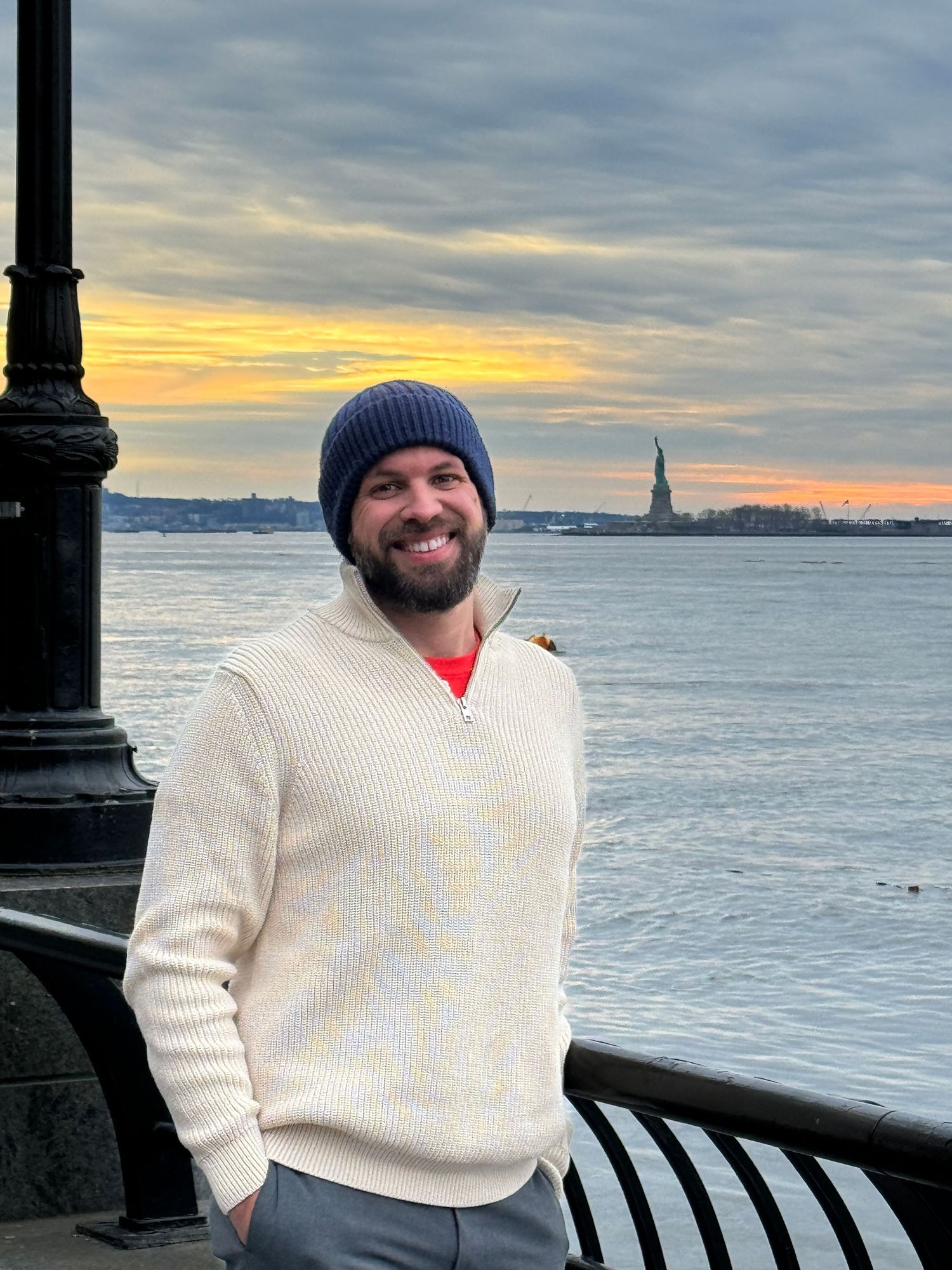 scenic sunset photos overlooking New York Harbor with the Statue of Liberty silhouetted in the distance.