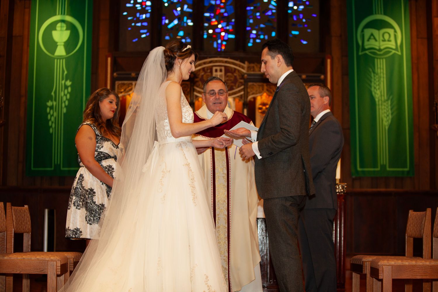 Traditional church wedding ceremony with stained glass windows and green accent lighting.