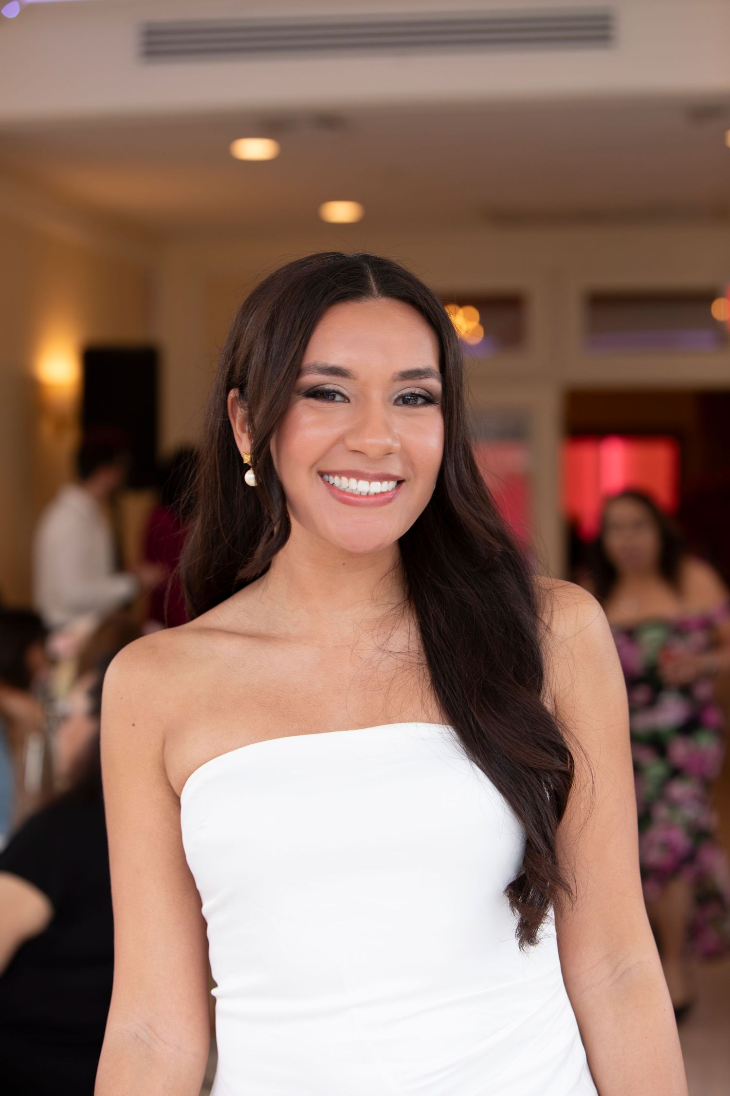 A radiant bride in a strapless white gown smiles during her wedding celebration.
