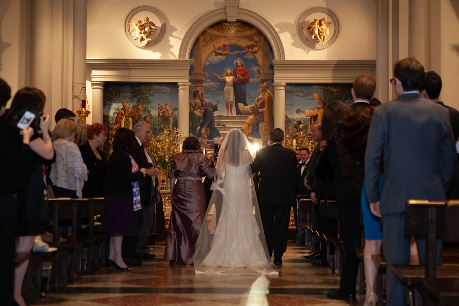 Wedding ceremony in ornate church with painted religious murals.