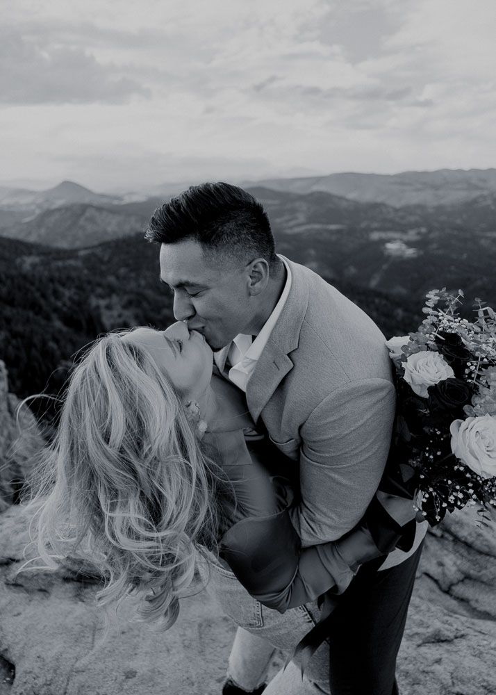 Black and white romantic portraits on mountain cliff with wind-swept hair.