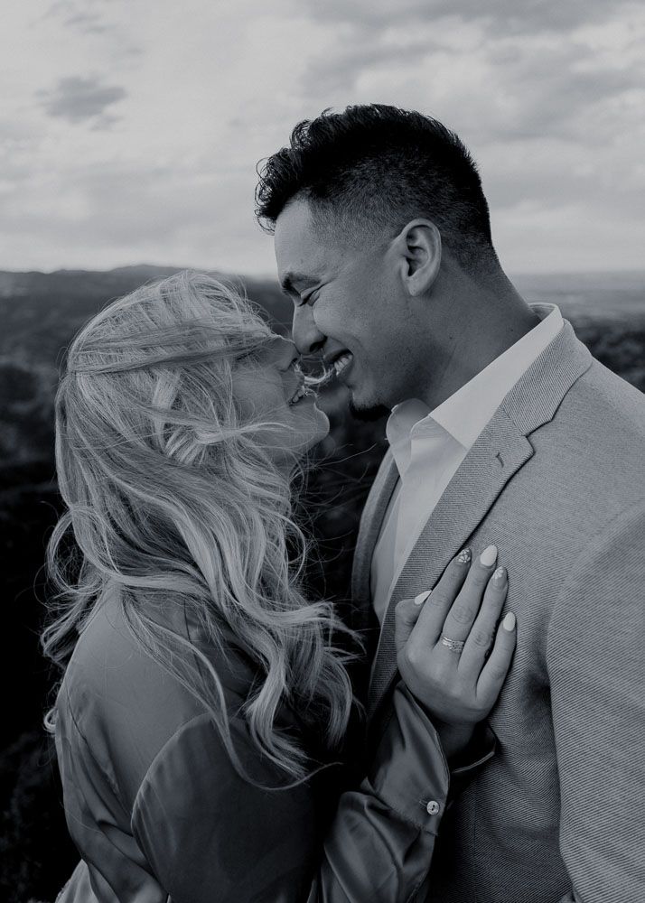Black and white romantic portraits against cloudy mountain backdrop.