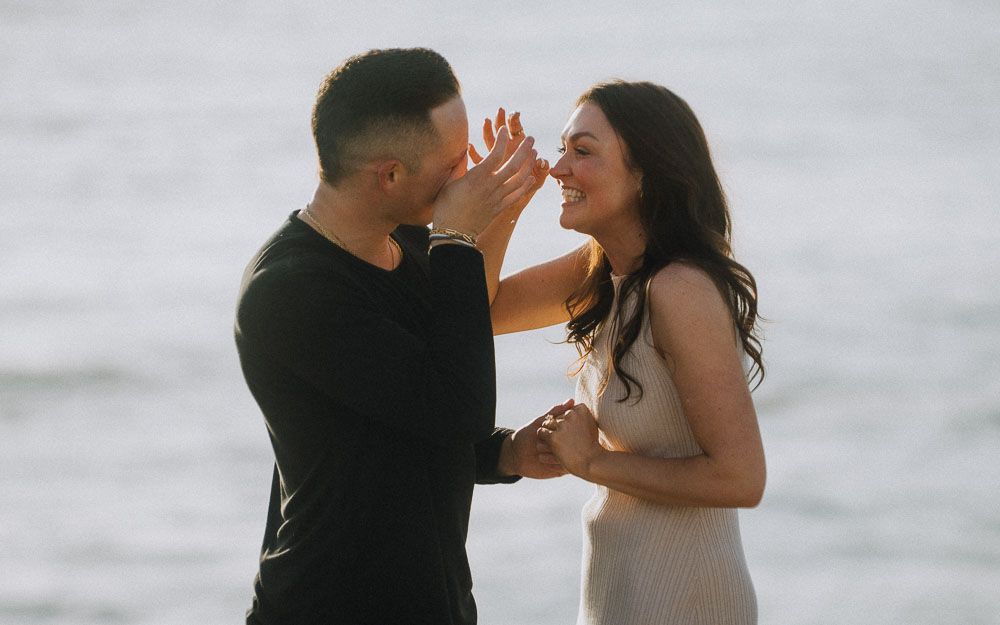 A couple taking in the moment after a surprise proposal on the coast.
