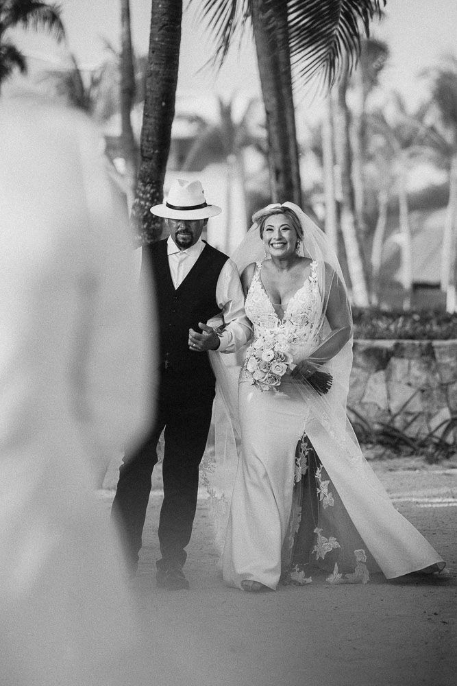 Candid black and white wedding photos captured under palm trees at a tropical destination.