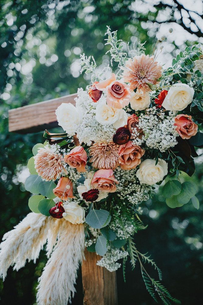 Beautiful wedding bouquet with coral and white roses, pampas grass, and delicate greenery.